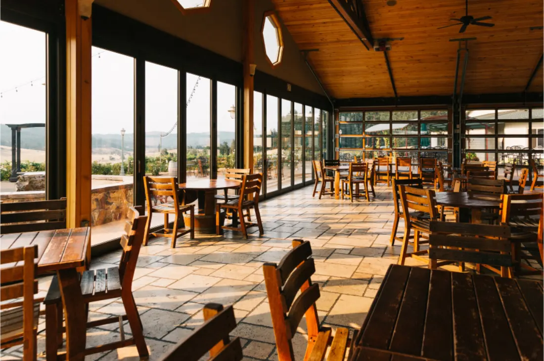 The Sweet Cheeks tasting room with wooden tables and chairs, timber ceiling and glass doors opened onto the patio and vineyard beyond